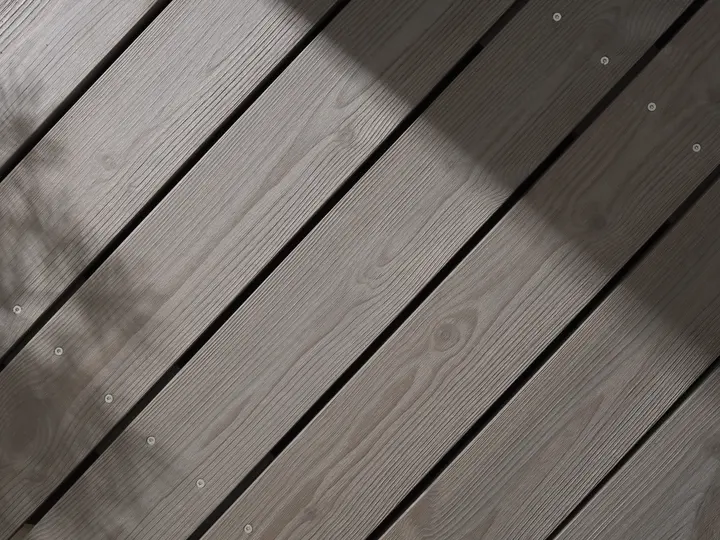 AGED-käsitelty harmaa terassi, jonka pinnalla lehtien varjoja.